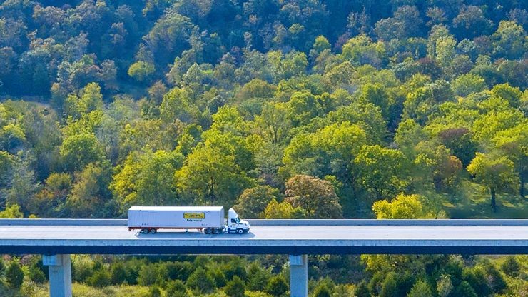 intermodal truck on a bridge with trees in the background