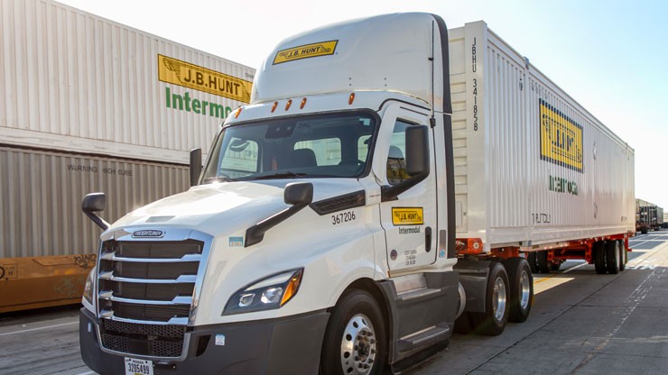white j.b. hunt truck and trailer White J.B. Hunt intermodal truck loaded with an intermodal container parks at a loading dock