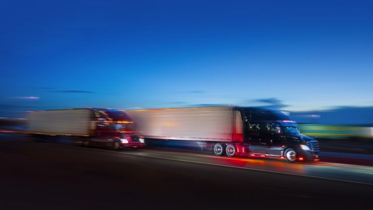trucks with motion blur driving on highway at dusk