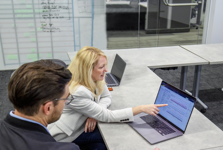 two J.B. Hunt employees point at graph on a laptop